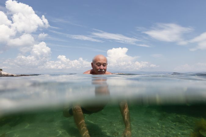 Cheerful mature man swimming in sea water