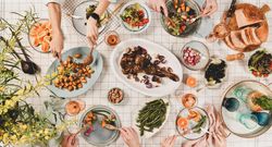 Flat-lay of Mediterranean table setting, with group of people at table, wide composition