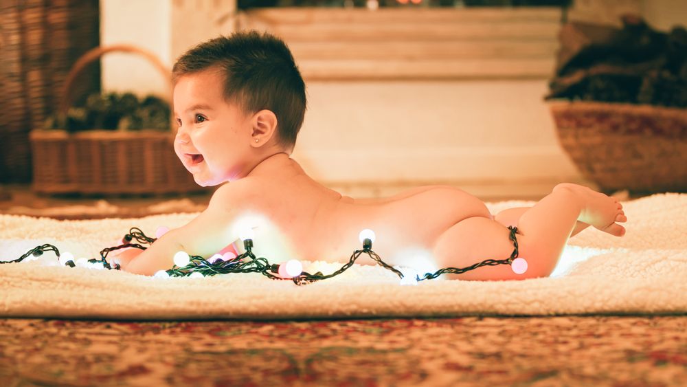 Baby playing with light garland on Christmas Day