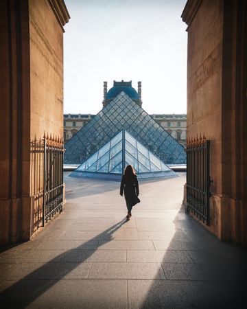 Back view of woman walking toward the Louvre museum in Paris, France