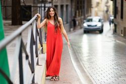 A charming woman in a vibrant red dress strolls gracefully through a scenic European street