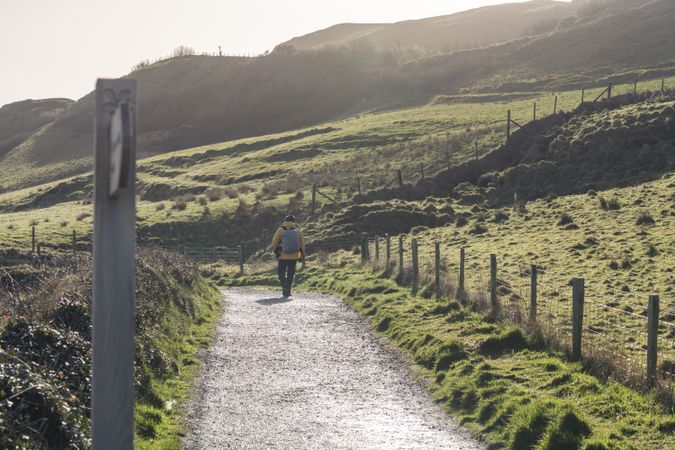 Woman walking on countryside road between fields