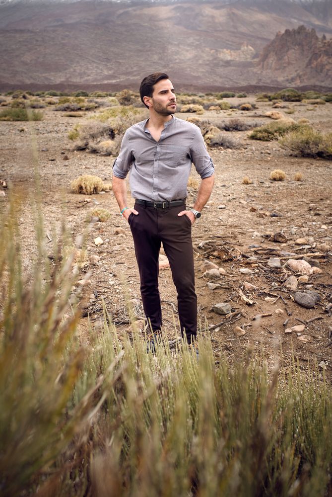 Stylish young male standing in rocky valley with savanna grass