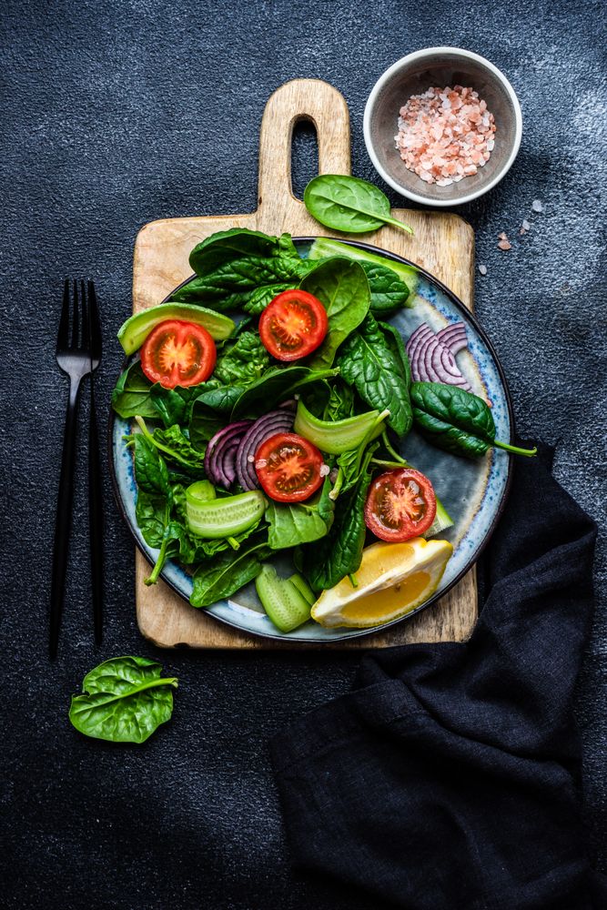 Top view of spinach salad with cherry tomatoes and red onions