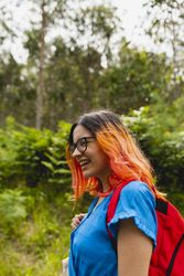 A young woman with orange hair smiles during a walk in a natural area in summer