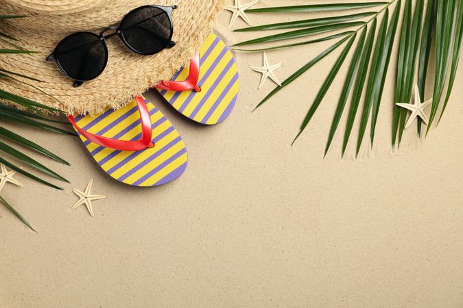 Summer vacation accessories on sea sand background, space for text
