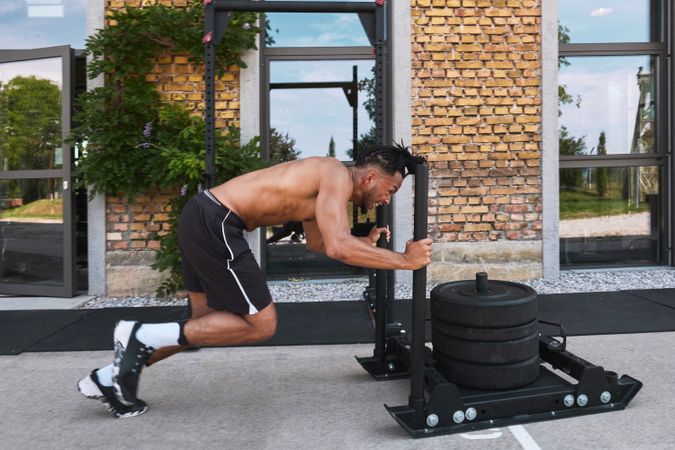 Black guy pulling weights in outdoor gym
