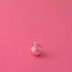 Pink Christmas bauble decoration on pink background