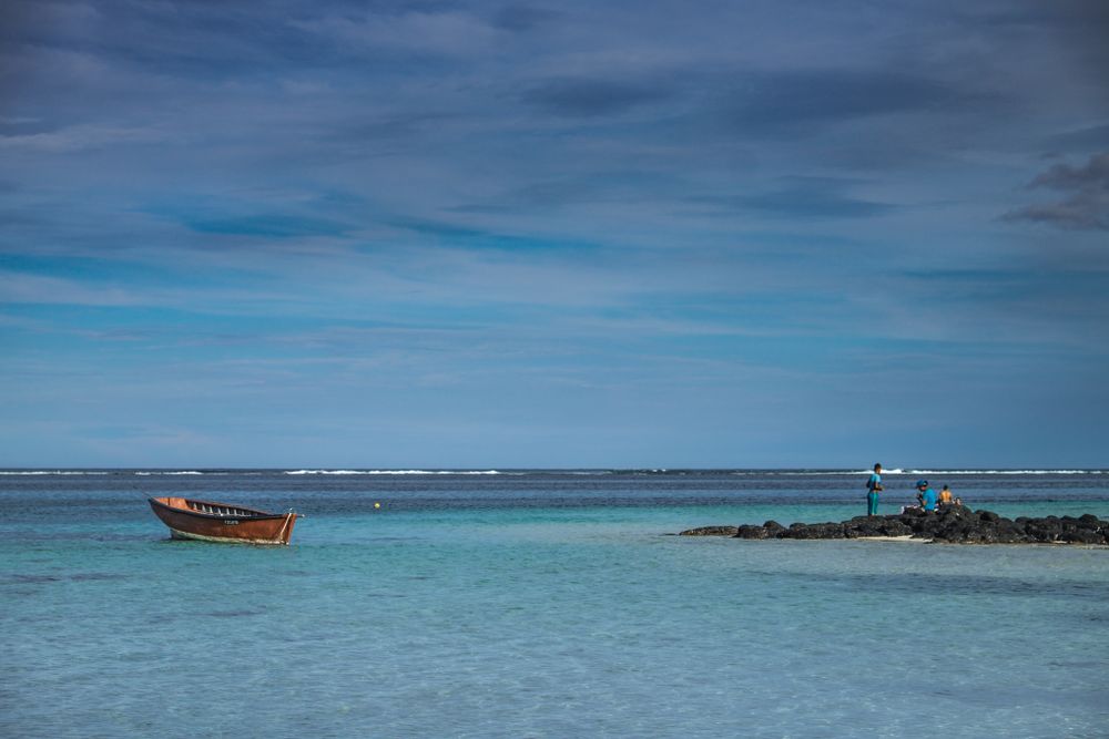 Red boat anchored in tropical lagoon in Mauritius near volcanic rock