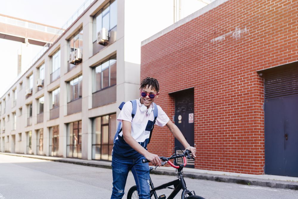 Young happy Black man standing with bike