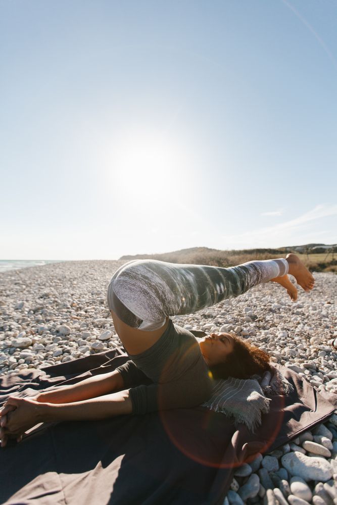 Sportive woman performing yoga posture in the beach