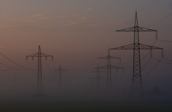 High voltage towers in a row on a foggy morning in a german village