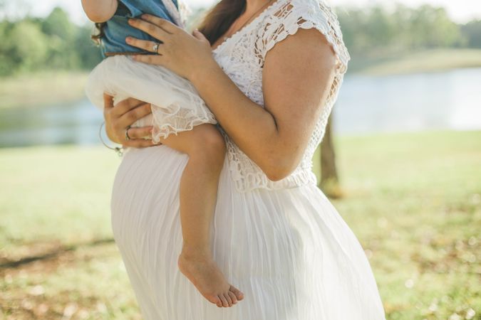 Pregnant woman in lace dress carrying a child
