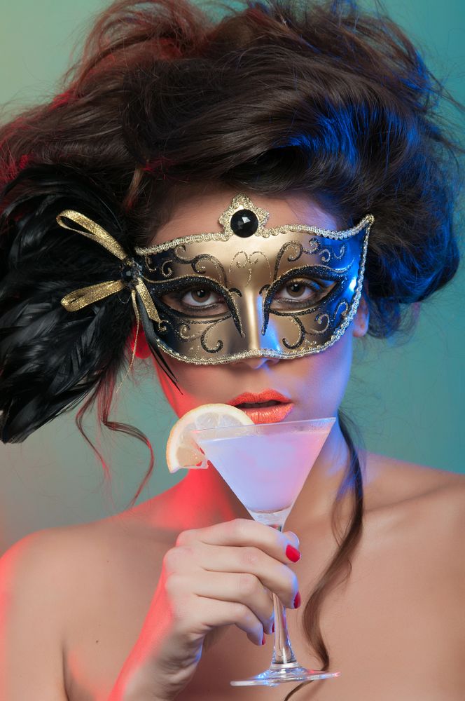 Woman in mask holding glass of drink