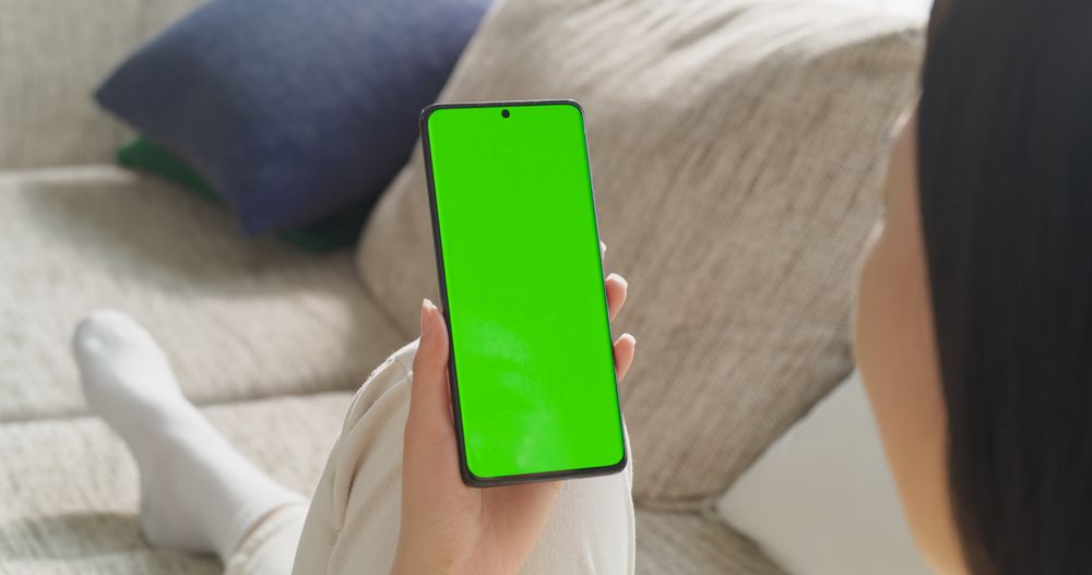 Anonymous Young Female Using a Smartphone with Green Screen Mock Up Display. Browsing Internet