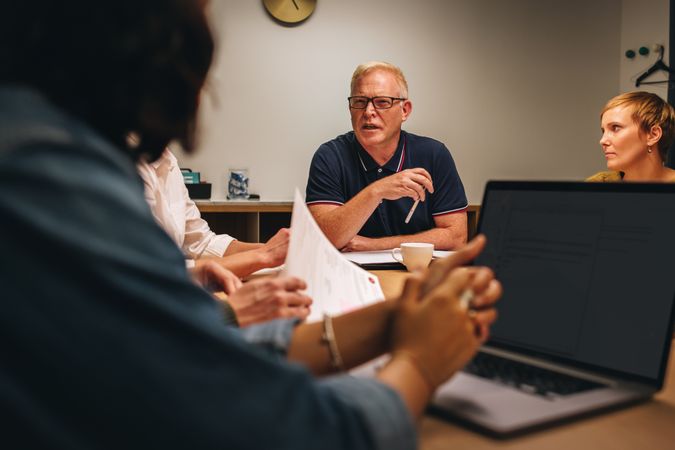 Mature man talking to colleagues in conference meeting