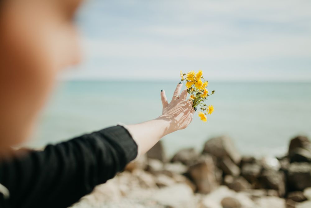 Anonymous woman throwing flowers in sea