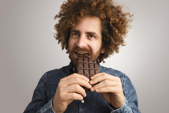 Man eating chocolate bar with two hands
