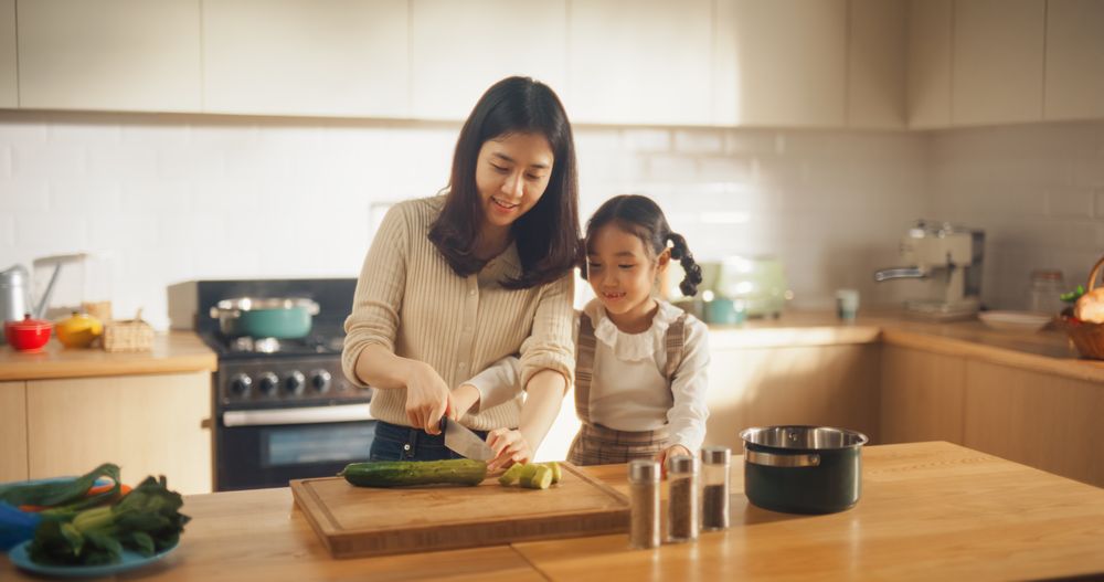 Beautiful Young Korean Mother Teaching her Cute Little Daughter How to Cook.