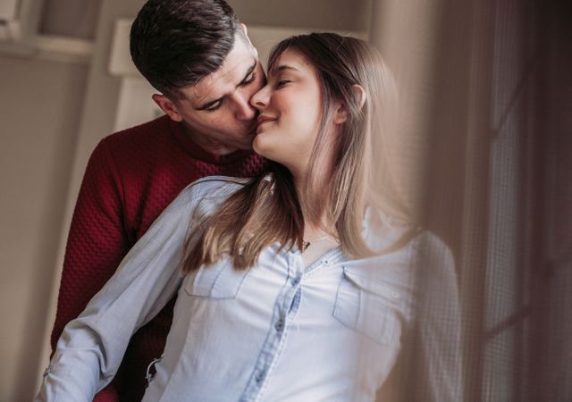 Pregnant woman with husband looking at window at home