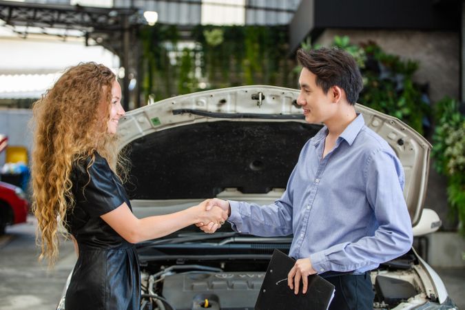 Car salesman shaking hand of female client after sale