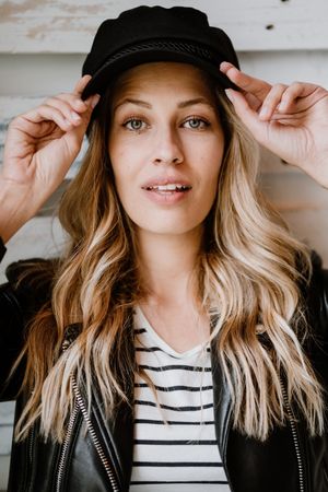 Woman thoughtfully looking at camera touching cap