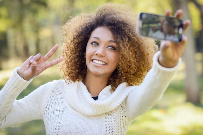 Smiling Black woman taking a selfie on her phone outside