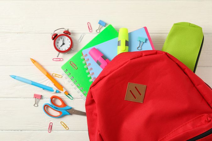 Flat lay composition with backpack and school supplies on wooden background