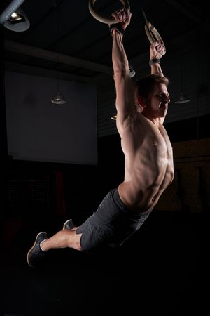 Fit man swinging on gymnastic rings