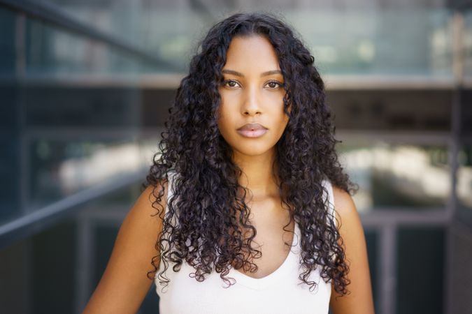 A confident and vibrant young woman with beautiful curly hair poses gracefully in an urban setting