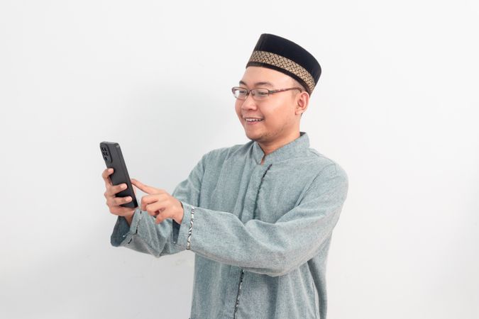 Asian Muslim man smiling holding phone pose, Ramadan
