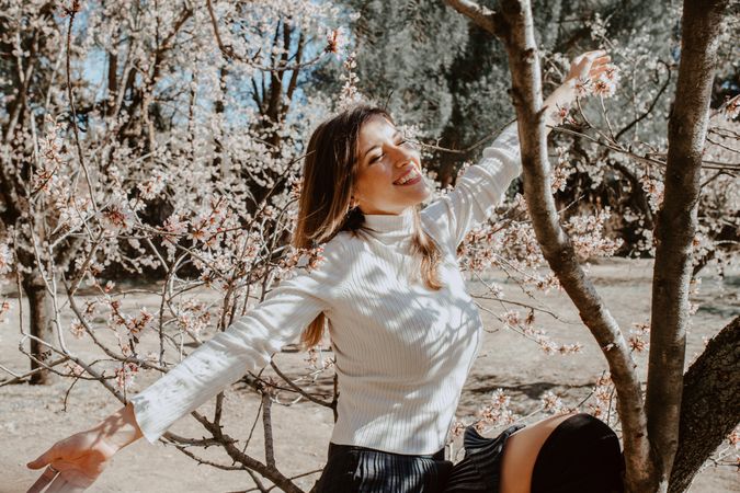 Young happy woman between trees in garden