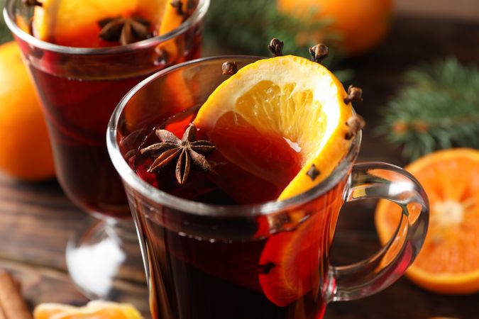 Glasses of tasty mulled wine with orange on wooden background, close up