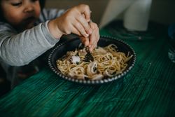 Girl eating from a bowl of pasta