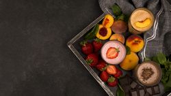 Top view of an assortment of milkshake glasses tray with fruits and chocolate