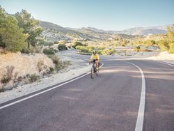 healthy man riding a bicycle on a mountain road in a sunny day