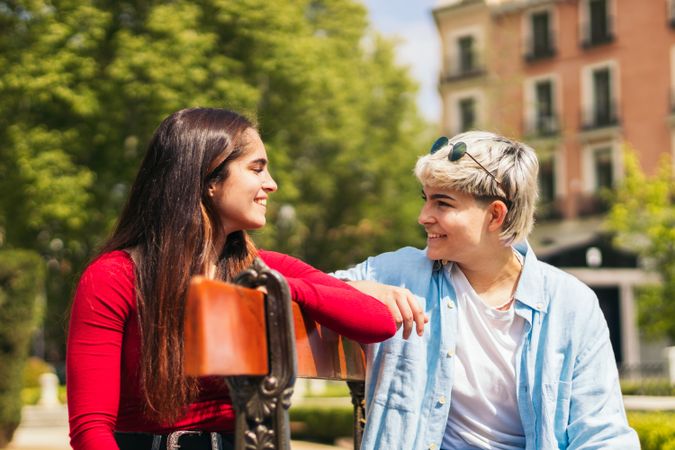 two women looking each other sitting on a bench