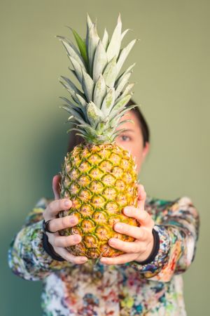 Woman holding pineapple in front of face
