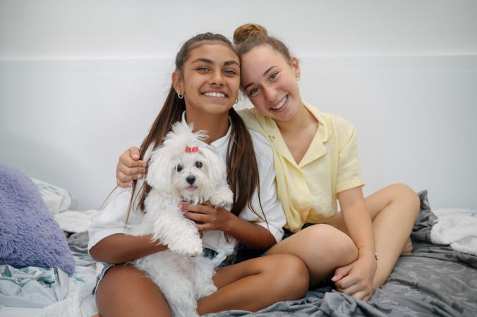 Happy girlfriends hugging with dog