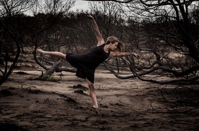 Woman dancing between dry trees