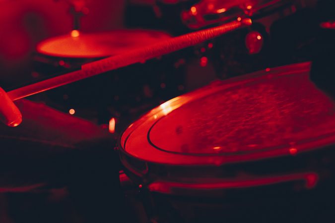 Man with drumsticks playing on drums in redness