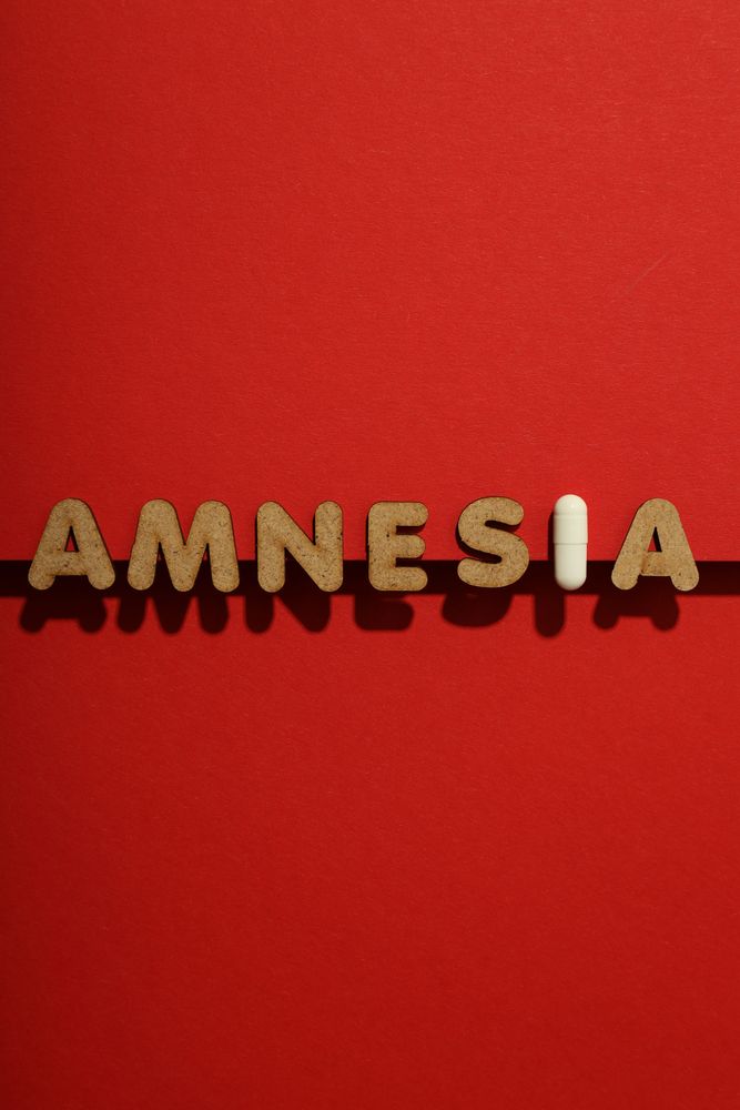 Cork letters of the word “Amnesia” with pill, in center of vertical composition