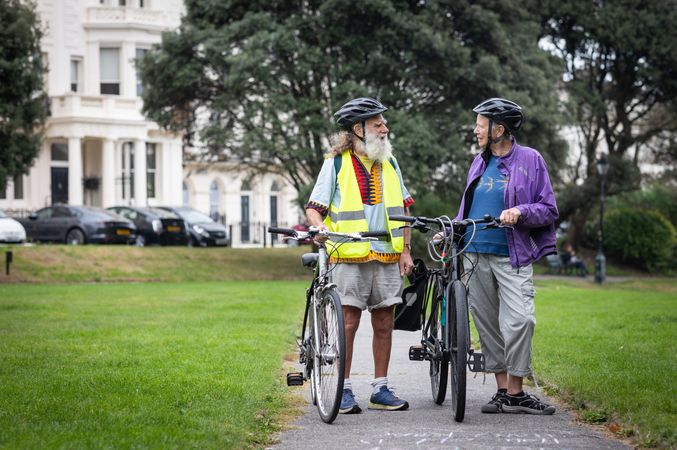 Two older people standing and talking with bikes with copy space