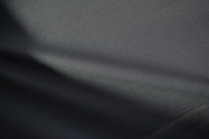 Wavy dark grey fabric background texture. shiny, glossy and elegant background.