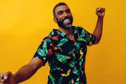 Smiling male dancing in brightly patterned shirt, copy space