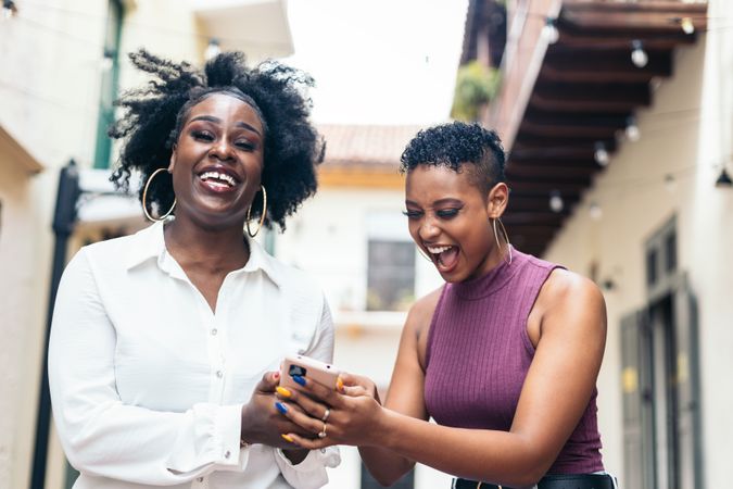 Happy women using mobile while walking in the city