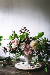 Composition of flowers and plants in vintage vase on board