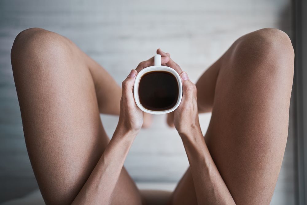 Faceless woman with coffee sitting in room at home