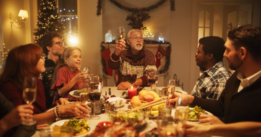 Parents, Children and Friends Enjoying Christmas Dinner Together in a Cozy Home in the Evening.