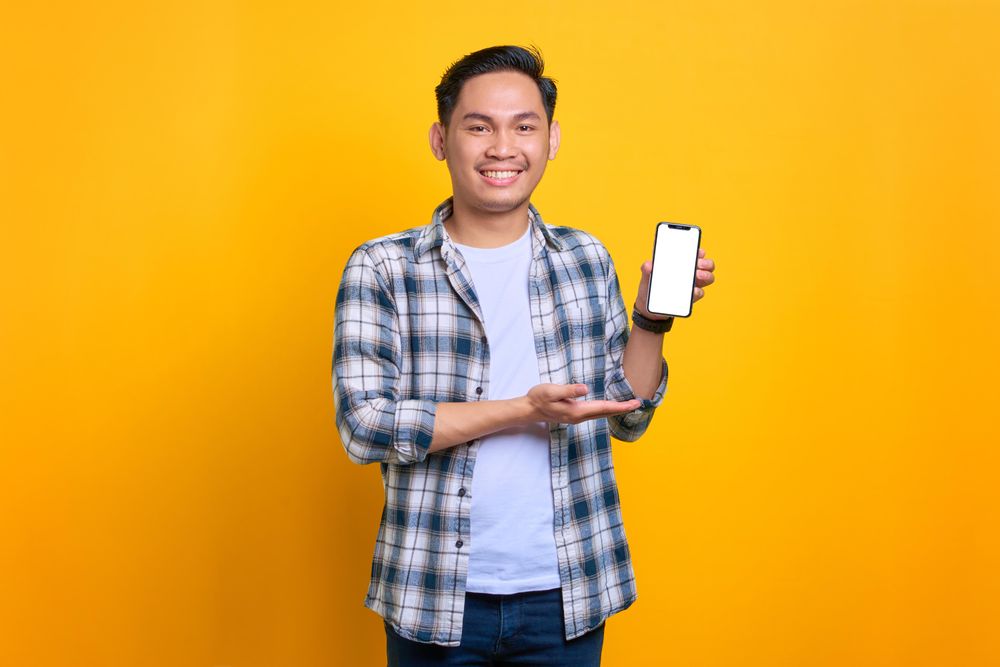 Asian male showing blank screen of smart phone in studio shoot